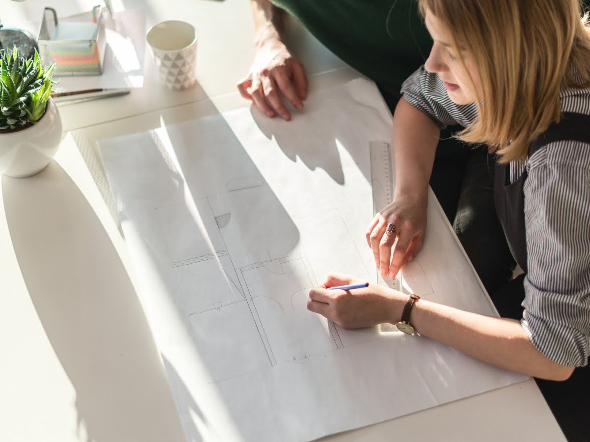 Two bathroom designers collaborating on a blueprint for Marietta remodeling services on a desk.