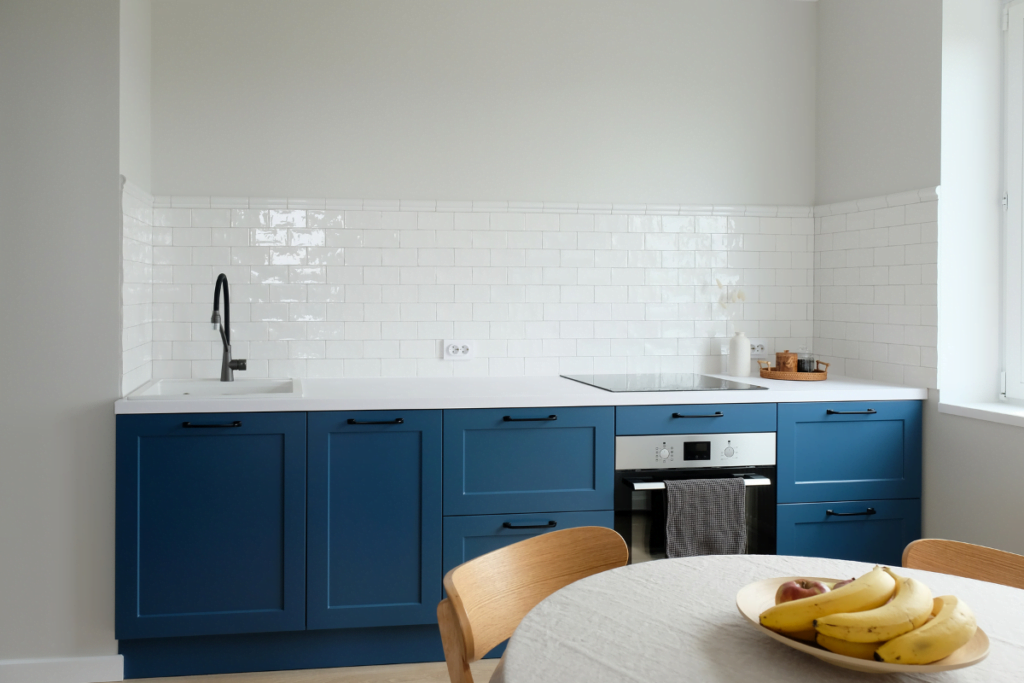 A coastal style kitchen with blue cabinets and a table.