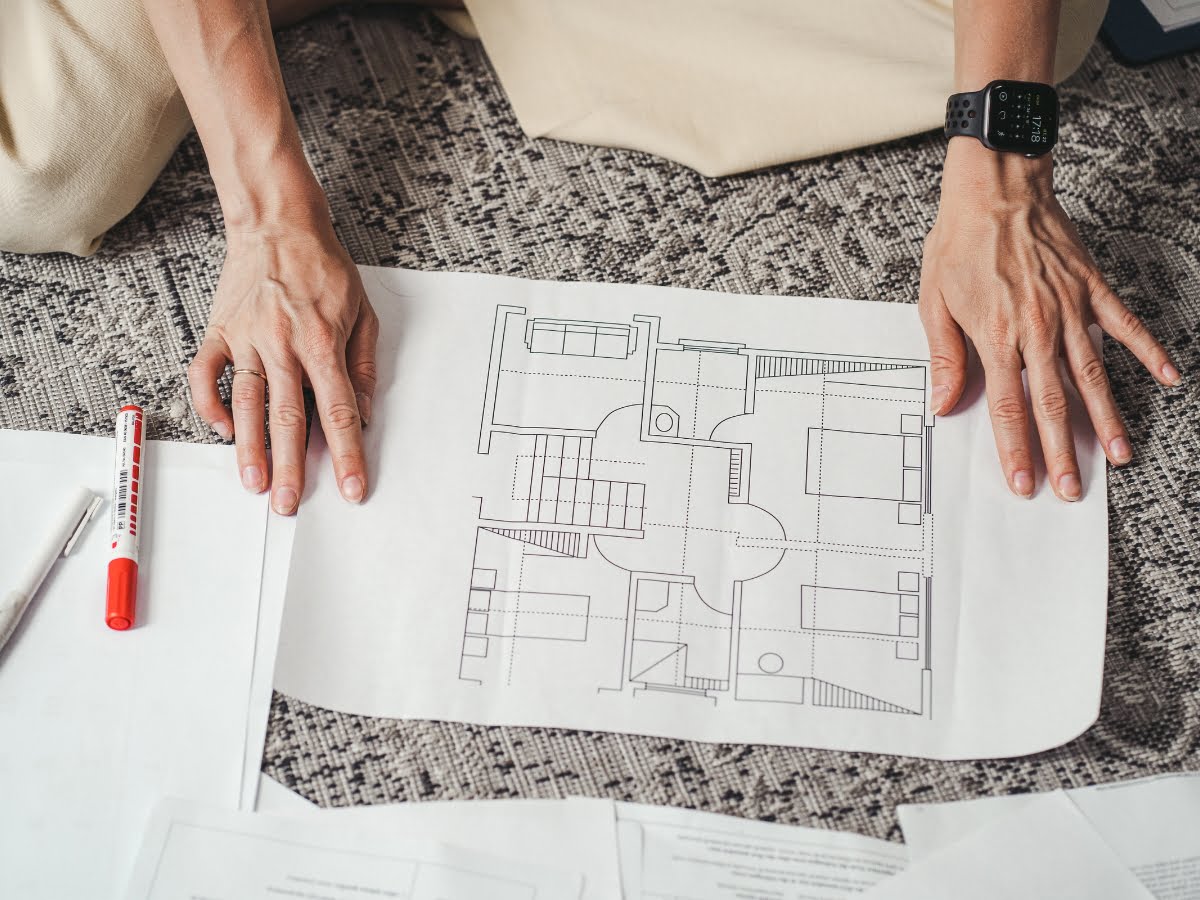 A woman is studying a blueprint of a location for flooring installation for Marietta remodeling services.