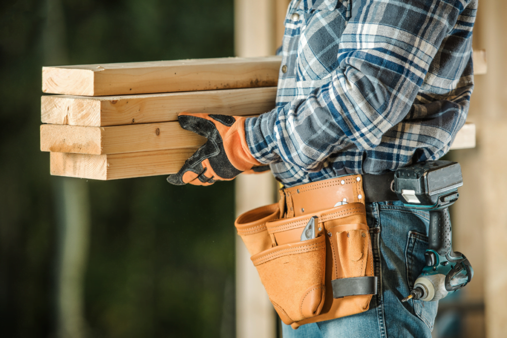 A construction worker holding a few pieces of wood.