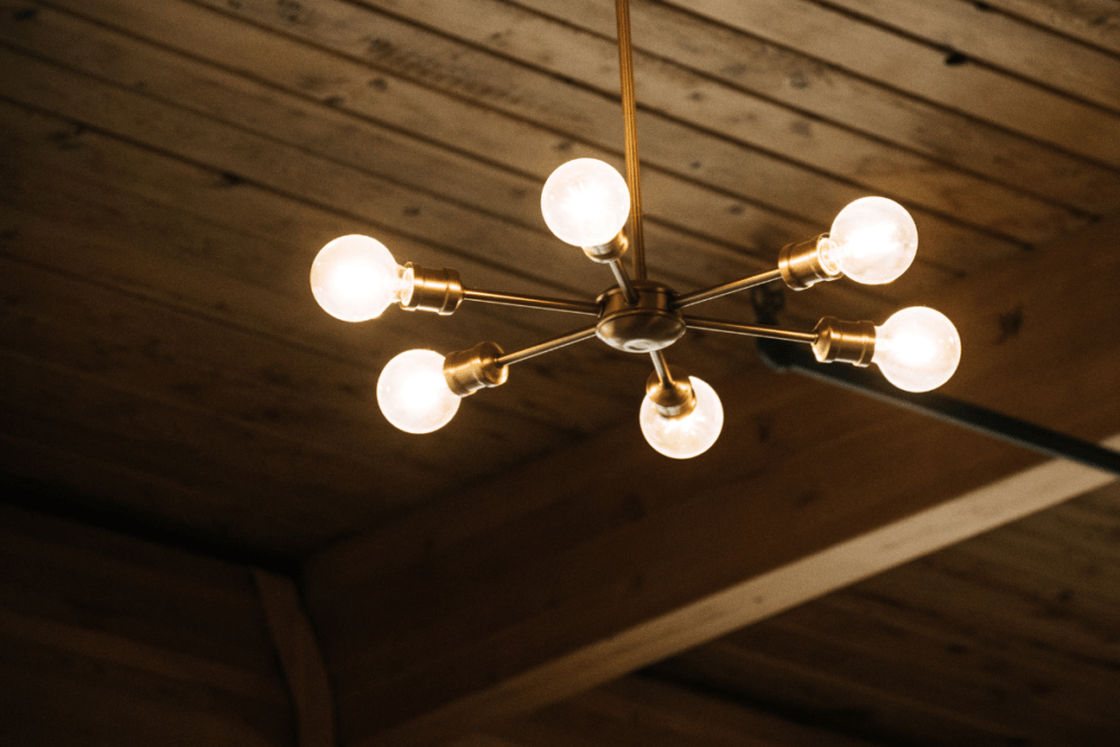 A colonial-style light fixture hanging from a wooden ceiling in a kitchen.