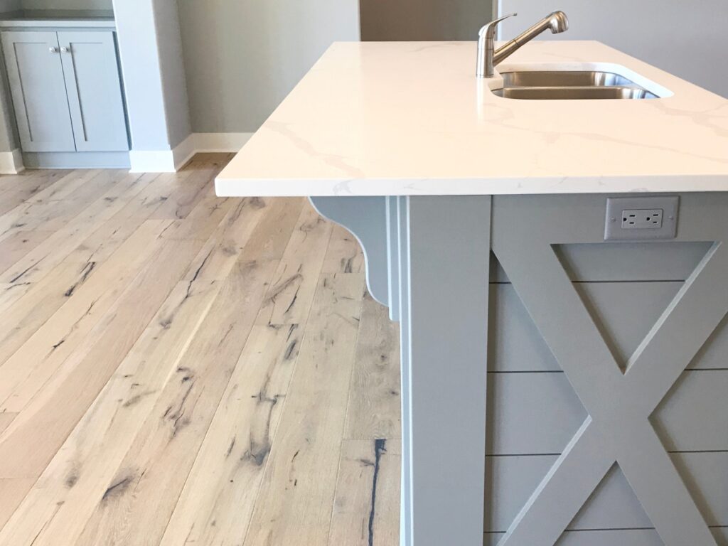 A white kitchen island with a gray countertop in a colonial style kitchen.