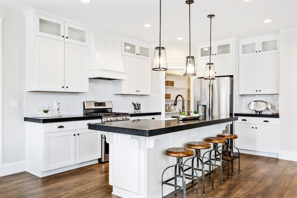 A white kitchen with black countertops.