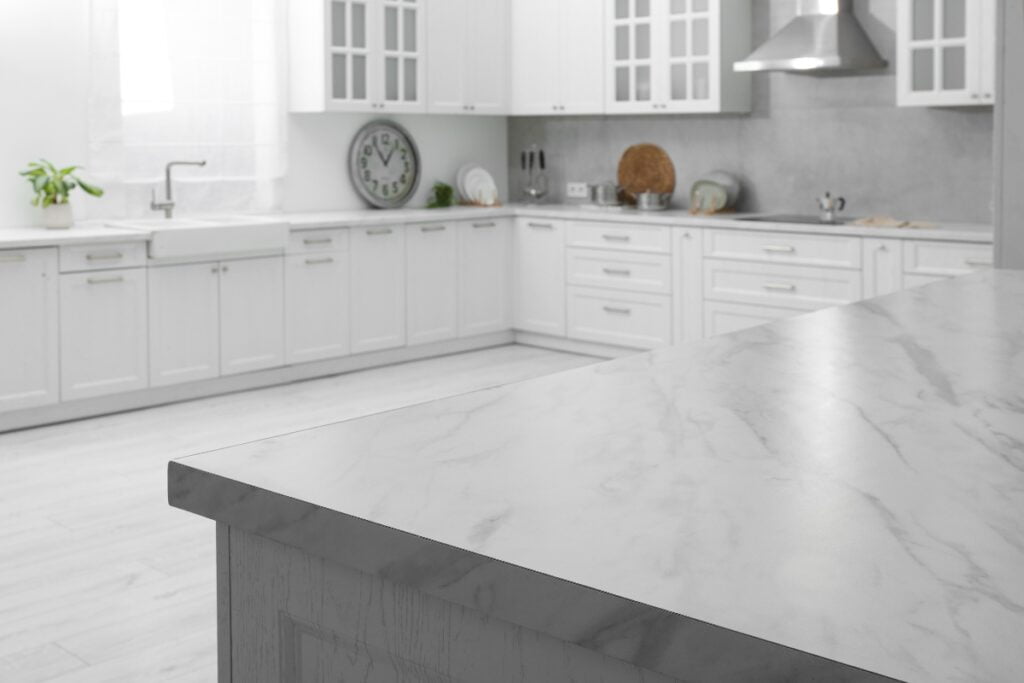 A white kitchen with a marble countertop and cabinets in various colors.