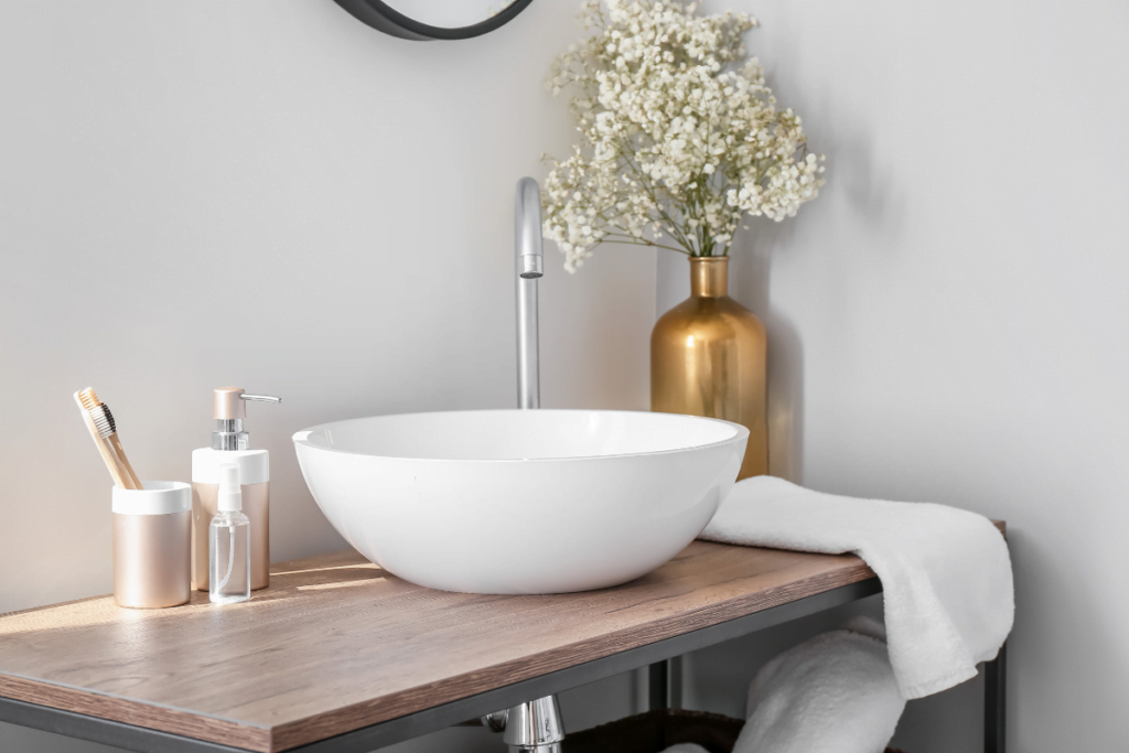 An eco-friendly bathroom featuring a white bowl sink on top of a wooden table.