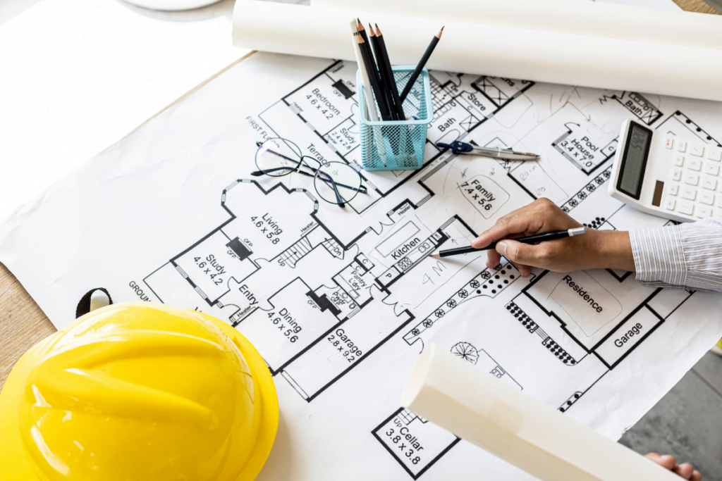 Architect reviewing blueprints with a pencil in hand, safety helmet on the side, for Atlanta Remodeling Contractors.