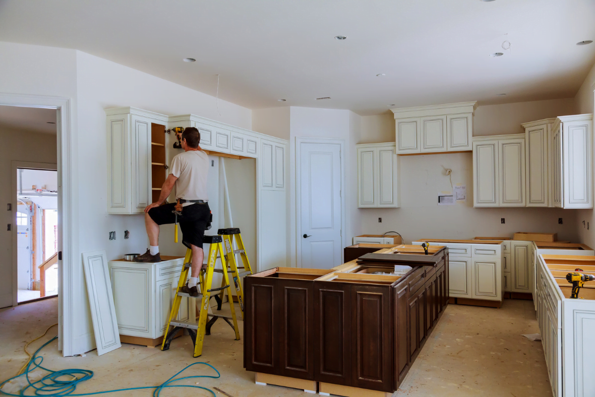 A man standing on a ladder doing a kitchen remodel.