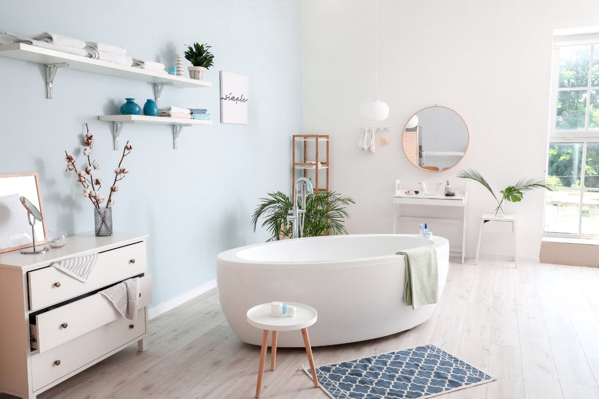 Bright and modern bathroom interior with a freestanding tub, vanity area, decorative elements, and innovative bathroom storage solutions.
