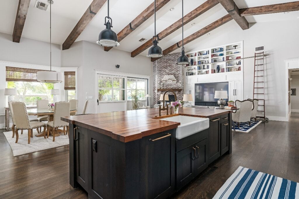 Modern kitchen maintenance tips for a space with a central island, exposed wooden beams, dining area in the background, and a loft ladder to the left.