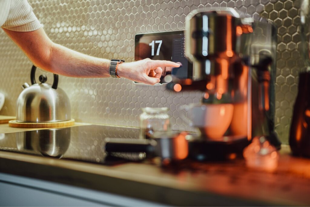 A person adjusting the settings on a smart coffee machine in a modern kitchen.