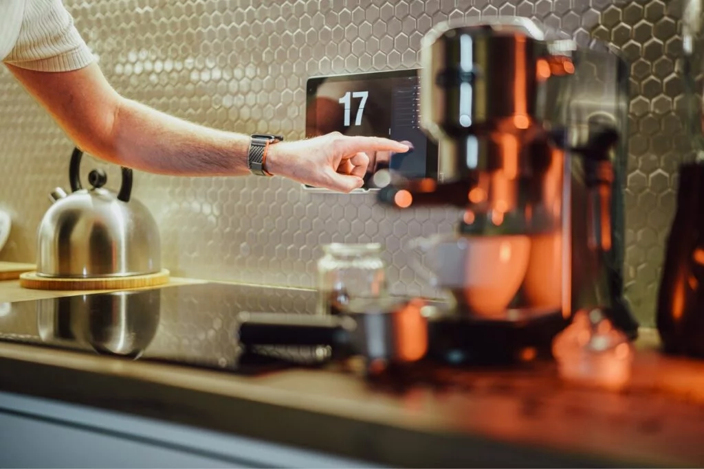 Smart Kitchen Technology: Revolutionizing Kitchens with Home Tech Integration 7 A person adjusting the settings on a smart coffee machine in a modern kitchen.