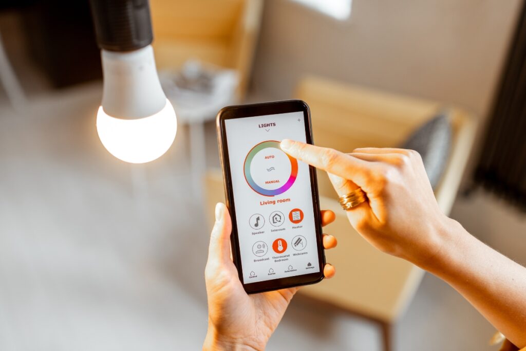 A person controls the brightness and color of a smart light bulb using a smartphone app in a modern, energy-efficient living room.