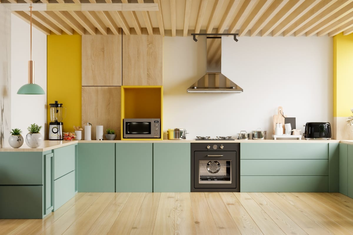 Vintage style kitchens meet modern elegance in this space, featuring teal cabinets, wooden countertops, and yellow accents. Appliances—stove, microwave, blender, and toaster—blend functionality with flair. Overhead lighting and potted plants complete the charming decor.