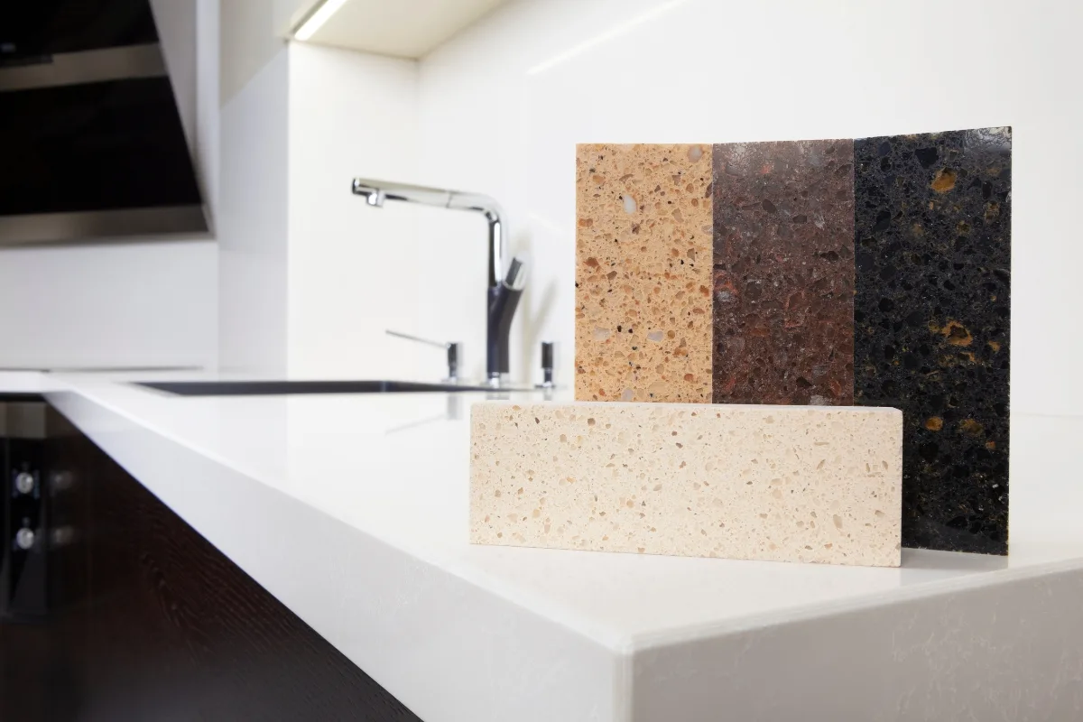 Top Kitchen Countertop Options for Your Sandy Springs Remodel 30 Samples of three different types of stone kitchen countertops are elegantly displayed on a white counter, complemented by a modern stainless steel faucet. Perfect for homeowners in Sandy Springs seeking inspiration for their kitchen renovation.