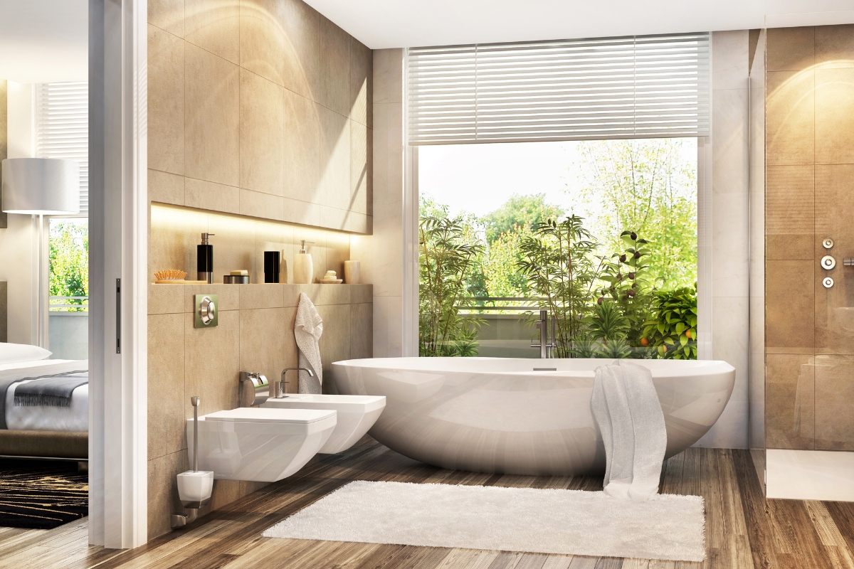 Elegant Bathroom Vanities in Roswell: Choosing the Right Style for Your Space 7 Modern bathroom with elegant bathroom vanities, a freestanding bathtub, bidet, large window with blinds, indoor plants, and wooden flooring; a bedroom is visible through an open sliding door.