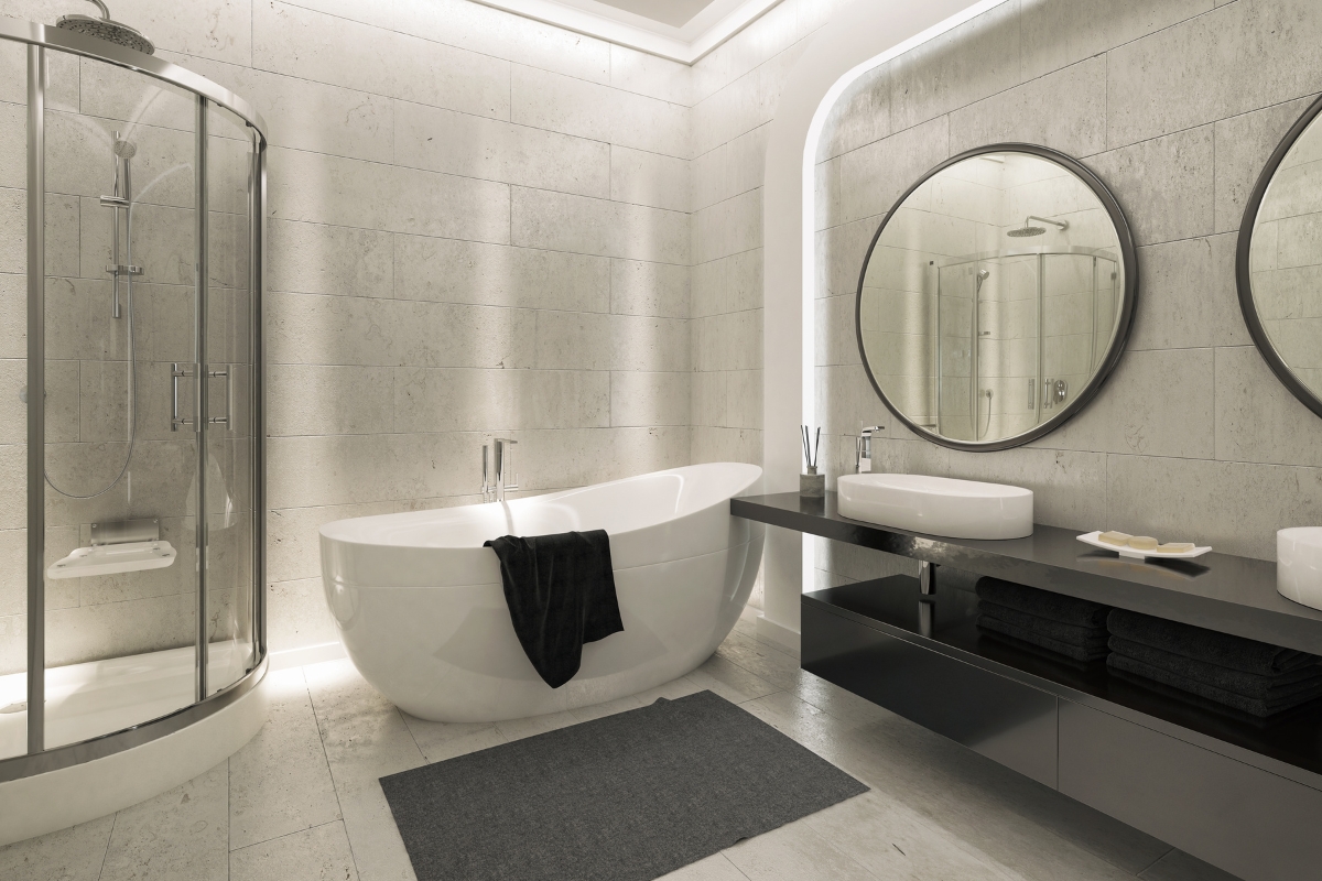 Elegant Bathroom Vanities in Roswell: Choosing the Right Style for Your Space 9 Modern bathroom with elegant bathroom vanities, a freestanding bathtub, glass shower, double sinks with round mirrors, dark towels, and soft ambient lighting.