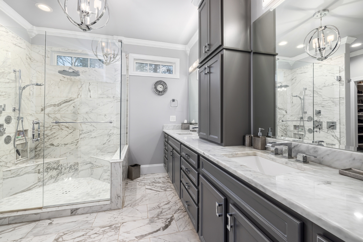 Bathroom Tile Flooring in Vinings: Expert Tips, Trends, and Benefits 2 Modern bathroom with gray cabinets, marble countertops, bathroom tile flooring, double sinks, and a large glass-enclosed shower.
