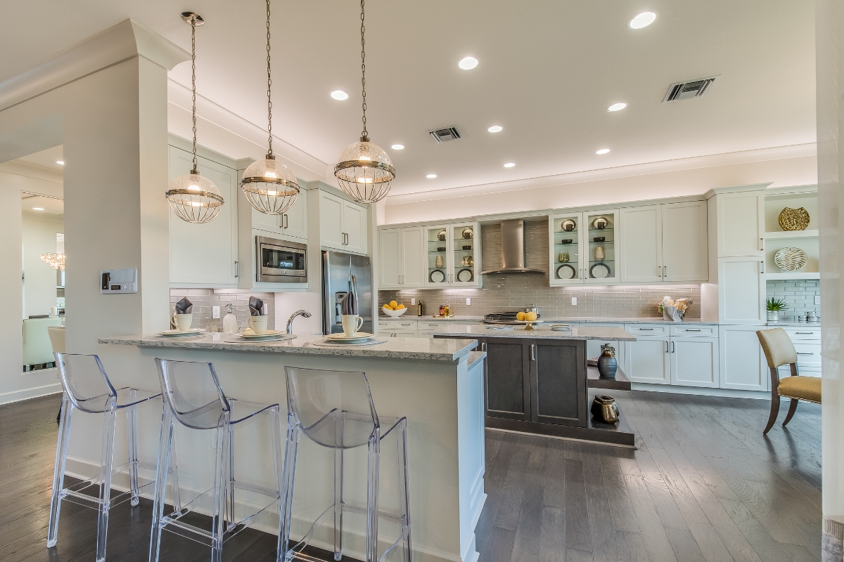 Luxury Kitchen Remodeling in Buckhead: Must-Have Features for 2025 4 Modern kitchen with white cabinets, a central island, pendant lights, and three transparent bar stools at the breakfast bar. This luxury kitchen remodeling project features bright recessed ceiling lights for a sleek, well-lit space.