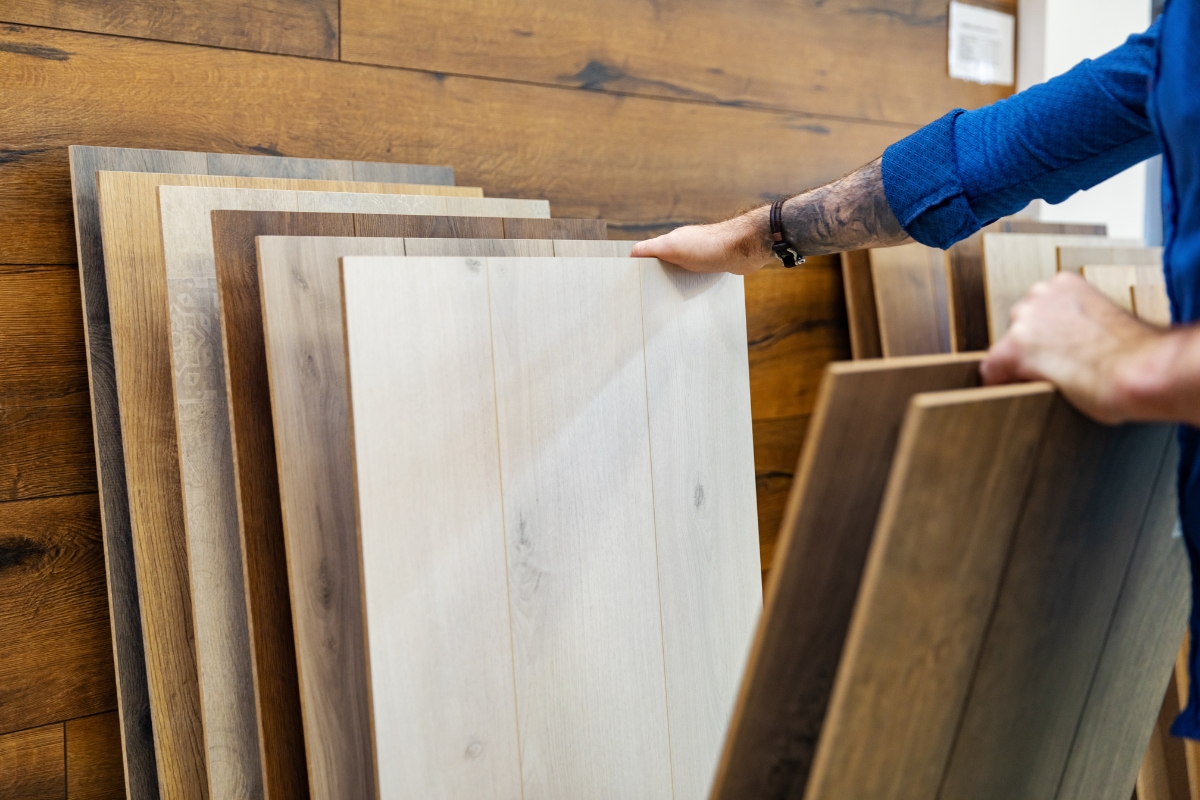 Luxury Kitchen Remodeling in Buckhead: Must-Have Features for 2025 7 A person selects a light-colored wood laminate flooring sample from a display of various wood tone panels, exploring options for their luxury kitchen remodeling project.