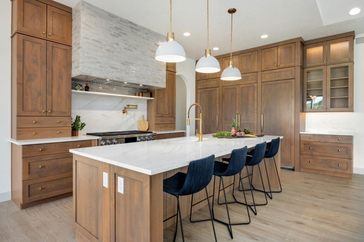Eco-Friendly Kitchen Remodeling in Smyrna: Sustainable Upgrades That Last 14 Modern, eco-friendly kitchen remodeling with wooden cabinets, a white marble island, four dark blue barstools, stylish pendant lights, and stainless steel appliances.