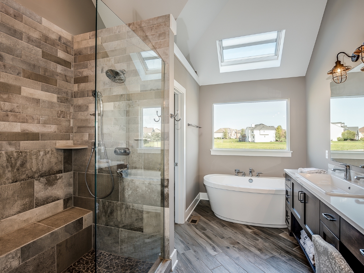 Walk-In Showers vs. Bathtubs in Johns Creek: Which Is Right for You? 13 Modern bathroom with a walk-in shower, freestanding bathtub, double vanity, large window, and skylights.