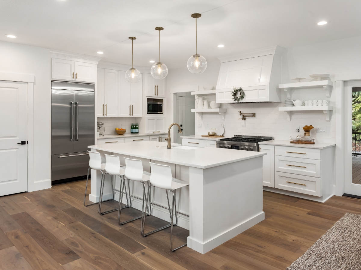 How to Select the Best Kitchen Flooring in Marietta GA: A Complete Guide 3 Modern kitchen with white cabinets, stainless steel appliances, an island with four white chairs, pendant lights, and beautiful wooden flooring—showcasing one of the best kitchen flooring options available.