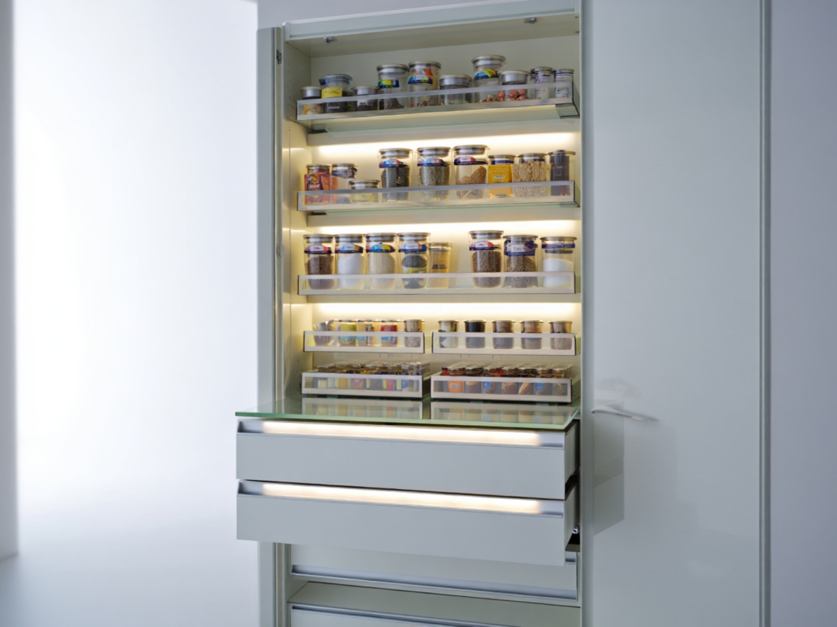 Essential Tips for Organizing Kitchen Cabinets 6 Open pantry cabinet with pull-out shelves and drawers, neatly organized with jars and containers of various spices and dry goods—perfect inspiration if you’re looking for tips for organizing kitchen cabinets.