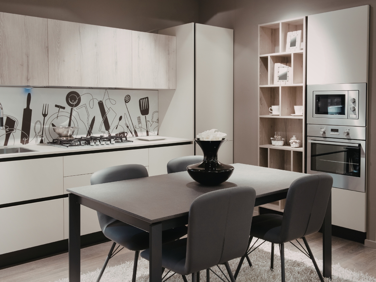 Modern kitchen with light cabinets, a gas stove, wall art of kitchen utensils, built-in oven and microwave, open shelves, and a dining table with four padded chairs—perfectly avoiding common Kitchen Staging Mistakes for a polished look.