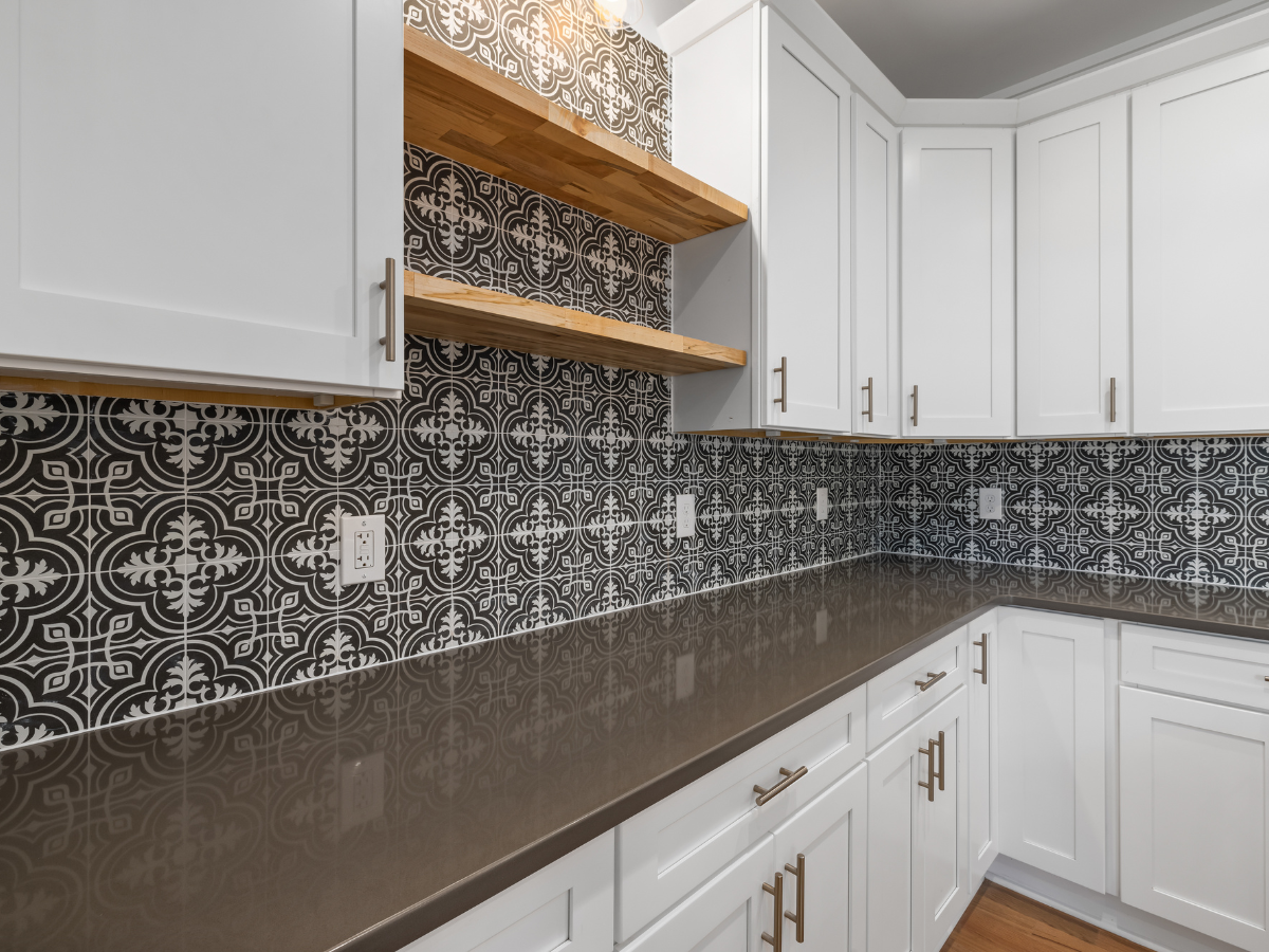 Popular Countertop Color Combinations for White Cabinets in Modern Kitchens 4 Modern kitchen with white cabinets, dark gray countertops, wooden open shelves, and a black and white patterned tile backsplash—showcasing stylish combinations for white cabinets.