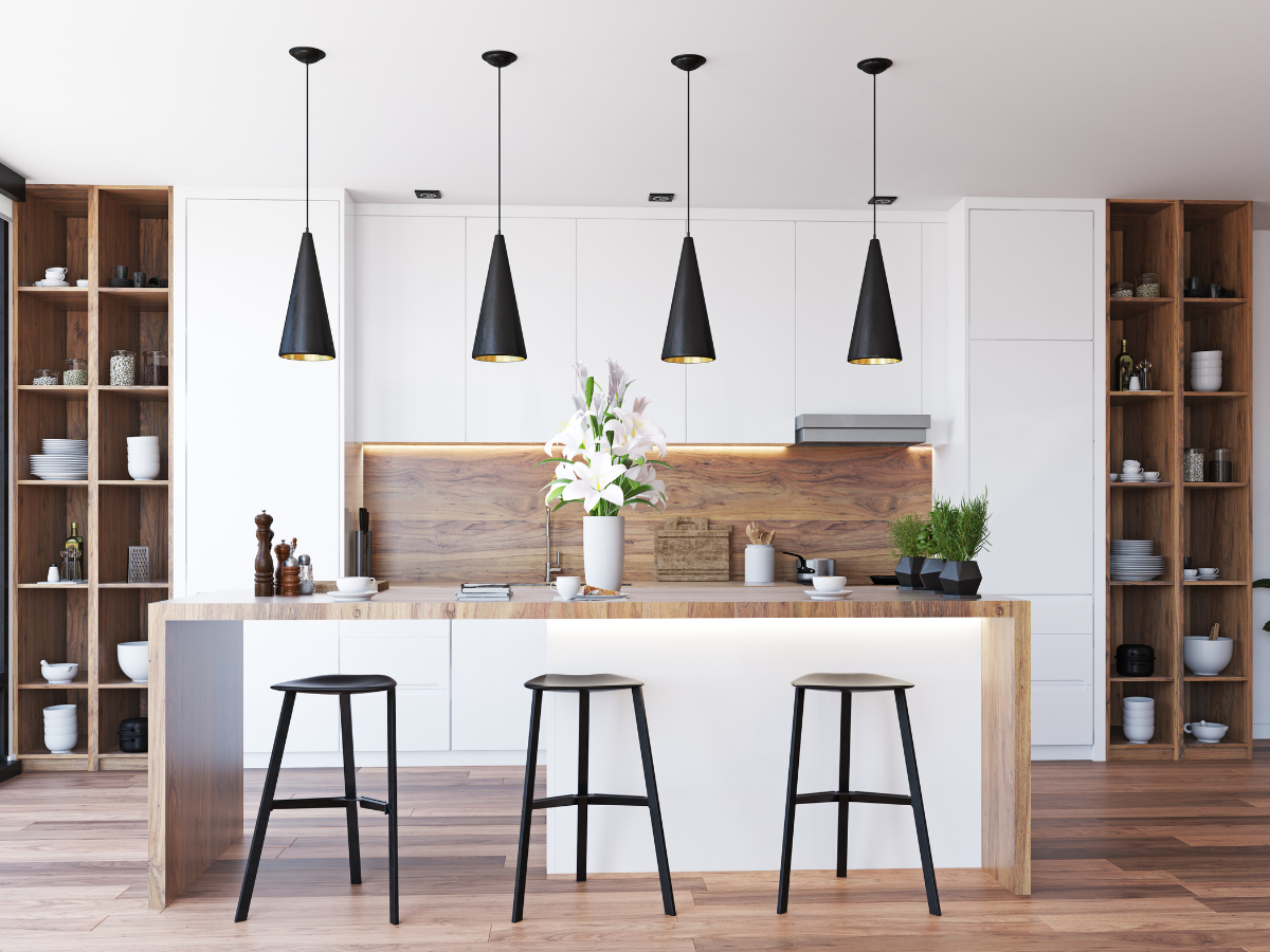 Popular Countertop Color Combinations for White Cabinets in Modern Kitchens 6 Modern kitchen with white cabinets, wooden accents, and stylish combinations for white cabinets. An island with three stools, black pendant lights, and open shelving displaying dishes and decor. A vase with flowers sits on the island.