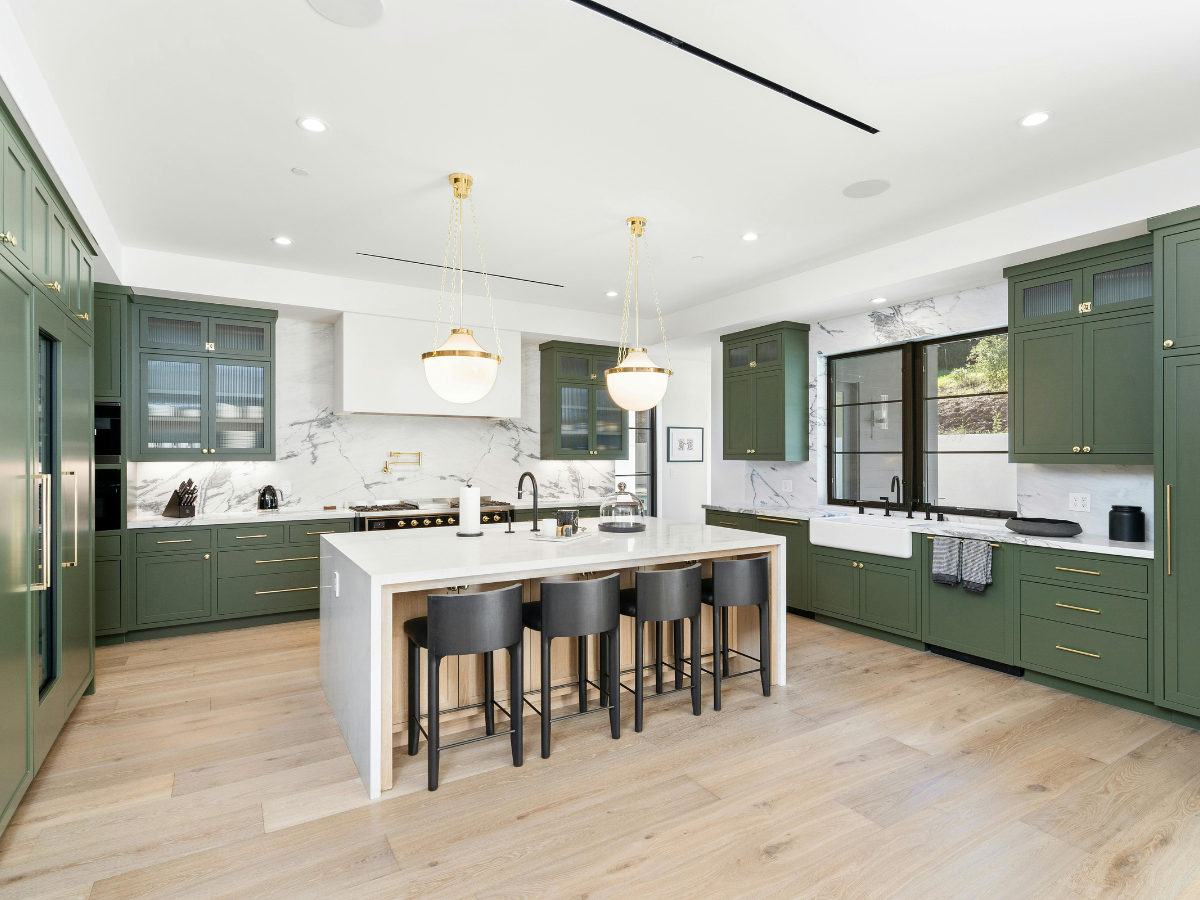 Kitchen Staging Ideas to Wow Potential Buyers: Expert Tips for Effective Home Selling 4 A modern kitchen with sage green cabinets, a white island with black stools, and marble backsplash—perfect for showcasing staging ideas.