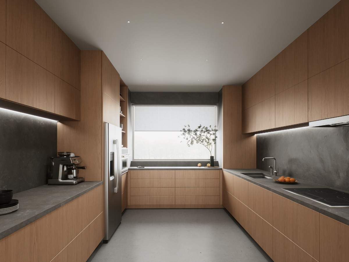 Modern integrated kitchen with light wood cabinets, gray countertops, built-in appliances, a coffee machine, and a window with a potted plant and bowl of oranges on the counter.
