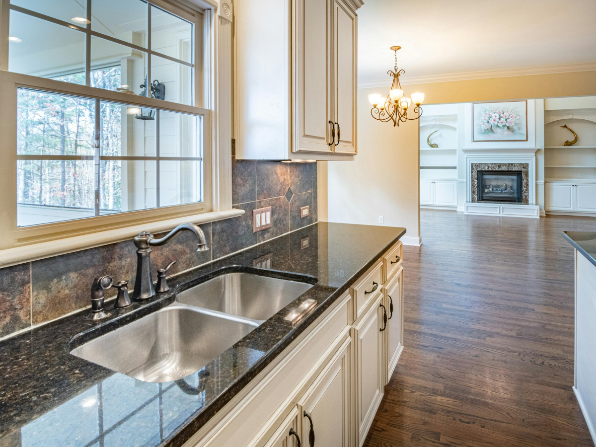 A Countertop Seams Guide to Fabrication and Installation 3 A kitchen with a double sink, dark granite countertops featuring expertly aligned countertop seams (see our handy countertop seams guide), white cabinets, and a view into a living room with a fireplace and hardwood floors.